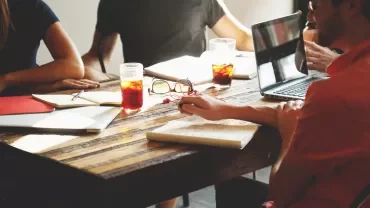 Personas reunidas en una mesa tomando notas con bebidas frías.