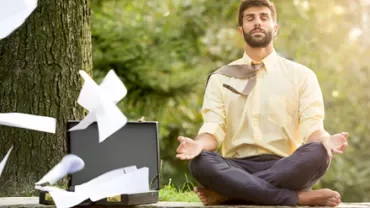 Persona meditando al aire libre con papeles volando.