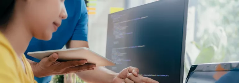 Personas colaborando frente a una pantalla con código.