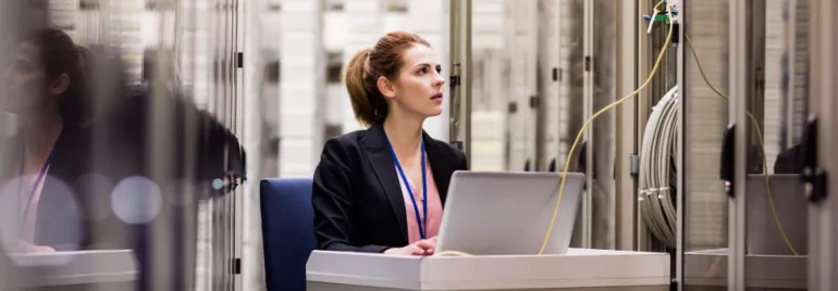 Persona trabajando en servidor de datos con computadora portátil.