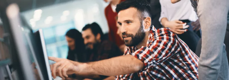 Personas colaborando frente a una computadora en una oficina moderna.