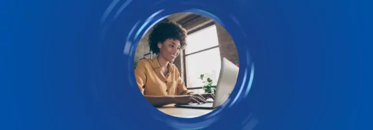 Persona trabajando en una laptop junto a una ventana.