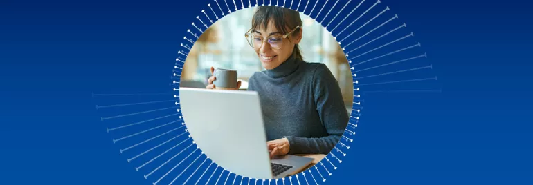 Persona trabajando en una computadora portátil con una taza en la mano.