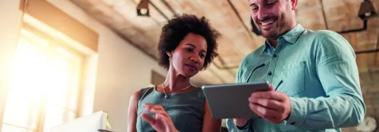 Dos personas revisando una tablet en un entorno de oficina.