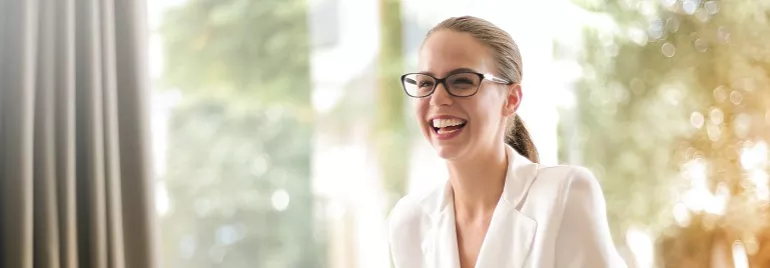 Persona sonriendo con gafas y una chaqueta blanca.
