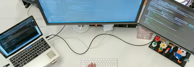 Trabajo en una estación de trabajo con portátiles y monitores que muestran código de programación.