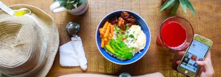 Vista cenital de un plato con verduras junto a un sombrero y bebida.