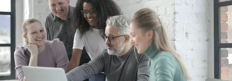 Grupo de personas trabajando juntos frente a un portátil.