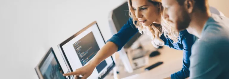 Dos personas revisando código en una computadora.
