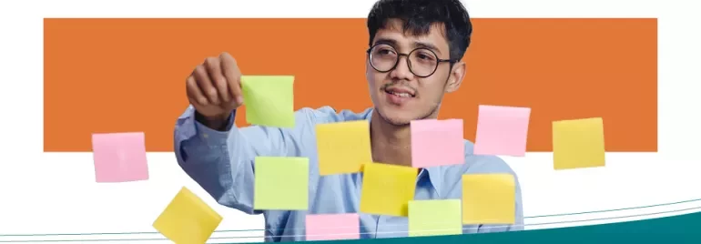 Persona organizando notas adhesivas en una pared.