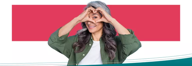 Persona mayor sonriendo, formando un corazón con las manos, sobre fondo rojo.