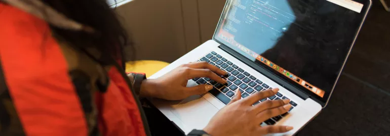 Persona escribiendo código en una computadora portátil.
