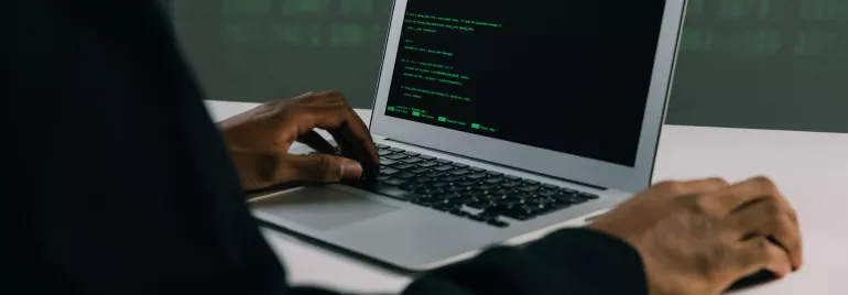 Persona escribiendo código en una laptop.