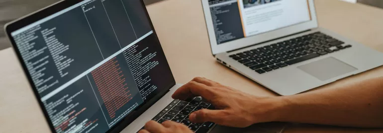 Persona escribiendo código en una computadora portátil en una mesa.