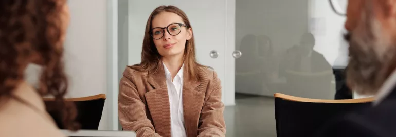 Reunión de negocios con tres personas sentadas alrededor de una mesa.