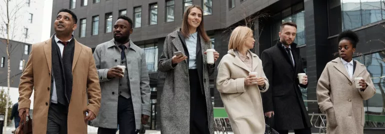 Grupo de personas caminando por la ciudad con abrigos y bebidas.