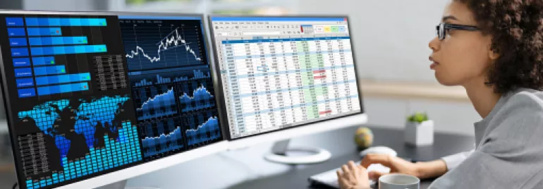 Persona trabajando en una computadora con gráficos de datos y hojas de cálculo.