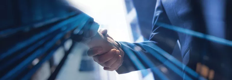 Dos personas dándose la mano en un entorno profesional.