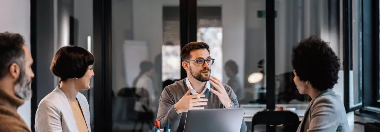 Grupo de personas en una reunión de negocios, conversando en una sala de reuniones.