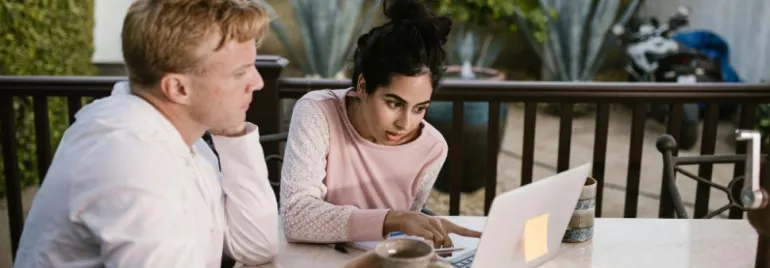 un chico y una chica mirando el ordenador mientras señalan algo en la pantalla