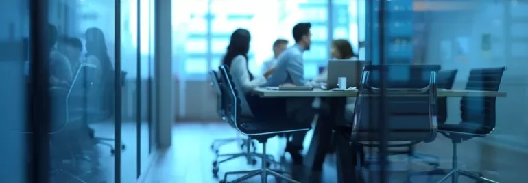 Equipo trabajando en un entorno empresarial, con un puesto vacío o silla libre que simbolice absentismo y rotación, reforzado por gráficos o dashboards de datos.