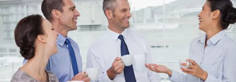 Grupo de personas conversando y bebiendo café en una oficina.