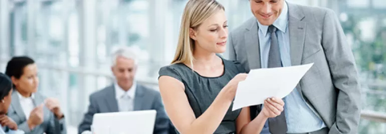 Personas trabajando en una oficina moderna, revisando documentos.