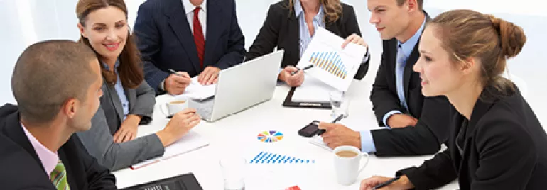 Reunión de equipo en una mesa con gráficos y computadoras portátiles.