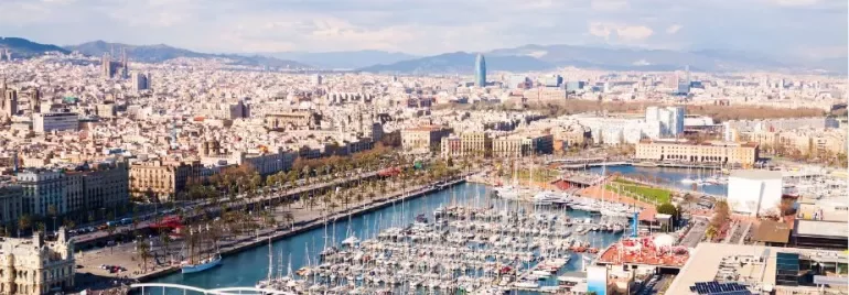 Vista aérea de un puerto lleno de barcos y una ciudad al fondo.