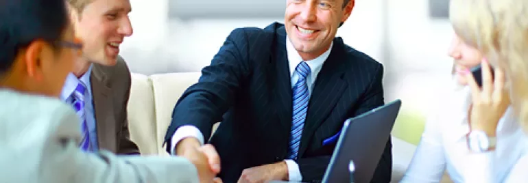 Personas en una reunión de negocios, sonrientes y estrechando manos.