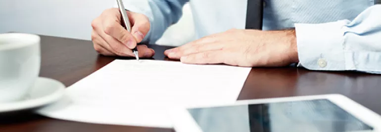 Persona firmando un documento en una oficina.