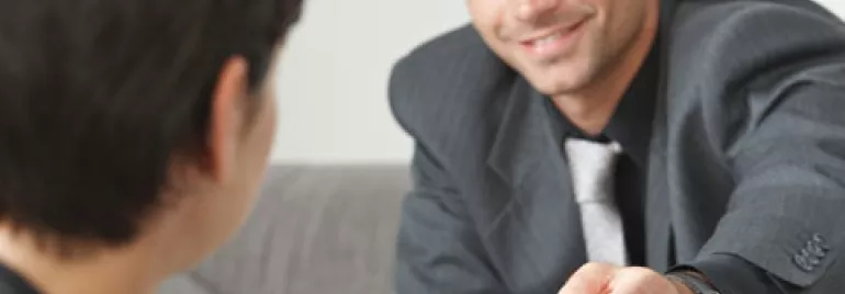 Persona entregando una tarjeta a otra persona en una reunión.