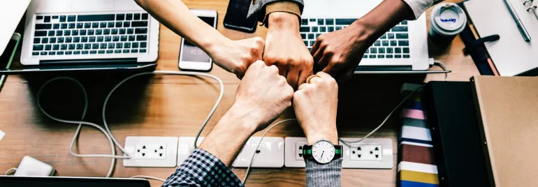 Cinco manos unidas sobre una mesa de oficina.