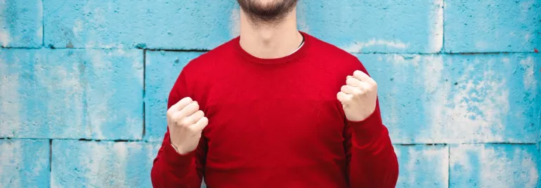 Persona sonriente vestida de rojo frente a un muro azul.