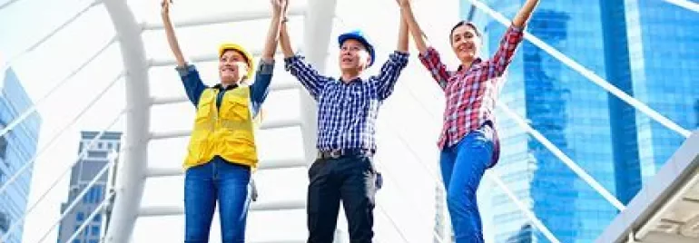 Trabajadores de la construcción levantan las manos juntos en una estructura moderna de la ciudad.