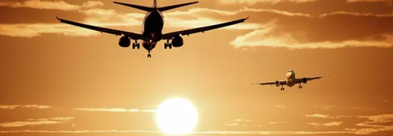 Dos aviones aterrizan al atardecer con el sol en el horizonte.