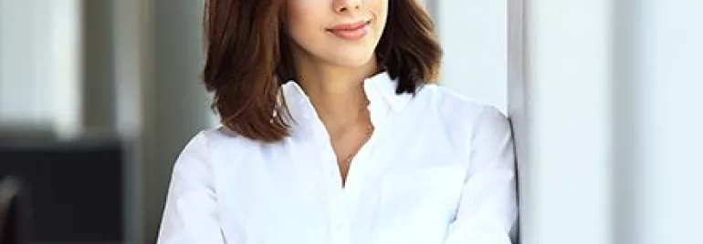 Persona sonriendo con una camisa blanca.