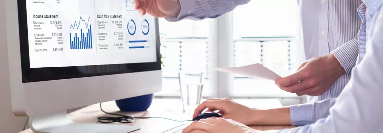 Personas analizando datos financieros en un monitor.