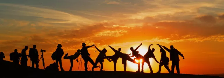 Personas en una colina al atardecer, capturadas en silueta.