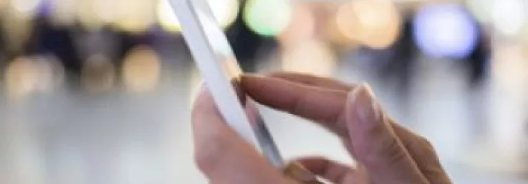Persona usando un smartphone con fondo difuminado.