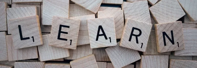 Letras que forman la palabra 'LEARN' en azulejos de madera.