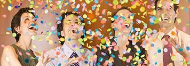 Personas celebrando con confeti colorido cayendo a su alrededor.