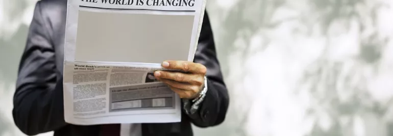 Persona leyendo un periódico con titular: El mundo está cambiando.