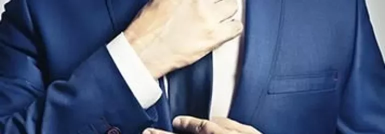 Persona ajustando una corbata azul.
