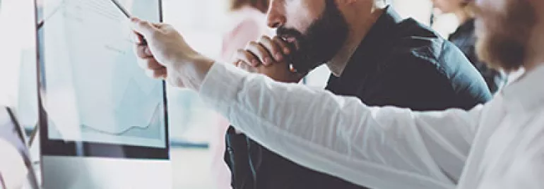 Personas trabajando en una computadora analizando datos.