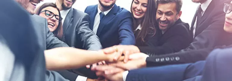 Grupo de personas uniendo sus manos en señal de trabajo en equipo.