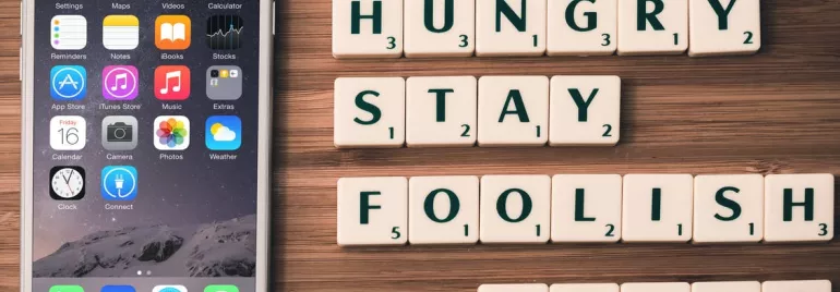 Teléfono junto a letras que forman la frase 'Stay hungry, stay foolish, Steve'.