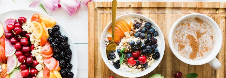 Mesa con frutas, yogurt, café y flores.
