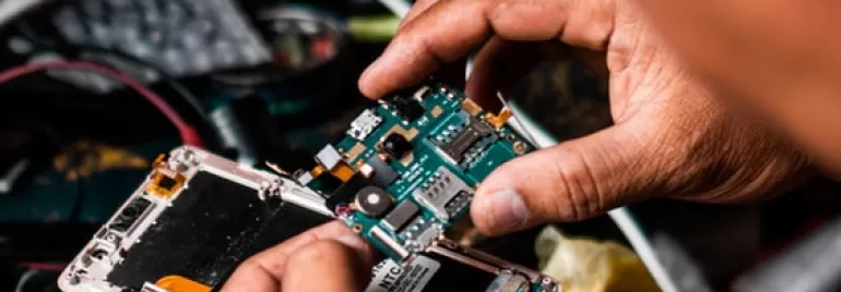 Manos arreglando las piezas internas de un smartphone.