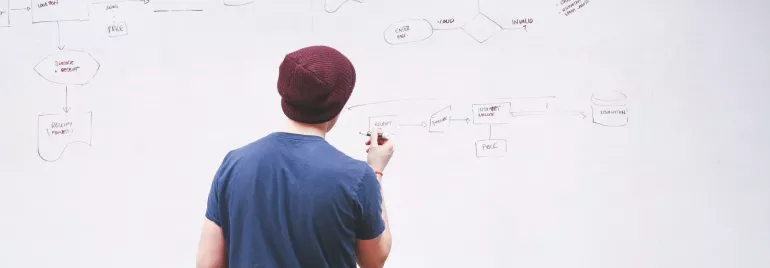 Persona escribiendo un diagrama en una pizarra blanca.
